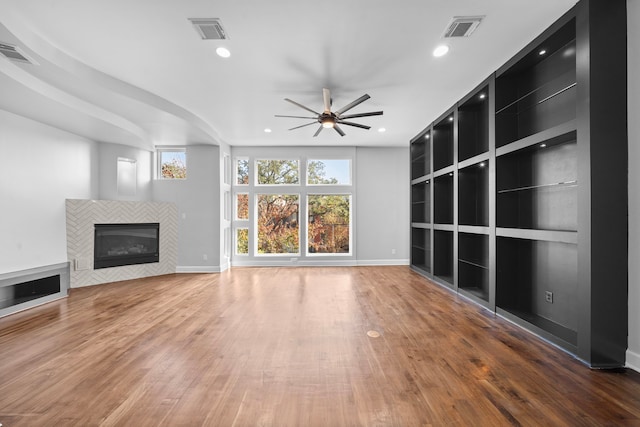 unfurnished living room featuring dark hardwood / wood-style floors, ceiling fan, and a tile fireplace