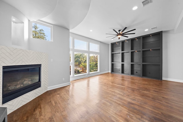 unfurnished living room featuring a fireplace, wood-type flooring, and ceiling fan