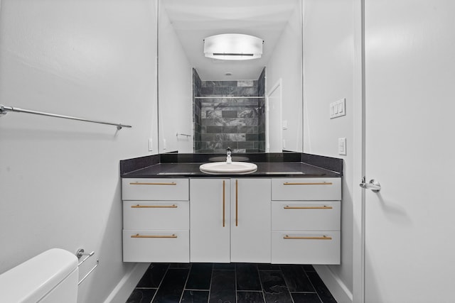 bathroom featuring a tile shower, vanity, and toilet