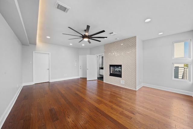 unfurnished living room with a tile fireplace, hardwood / wood-style flooring, and ceiling fan