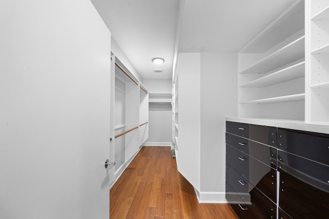 walk in closet with light hardwood / wood-style flooring