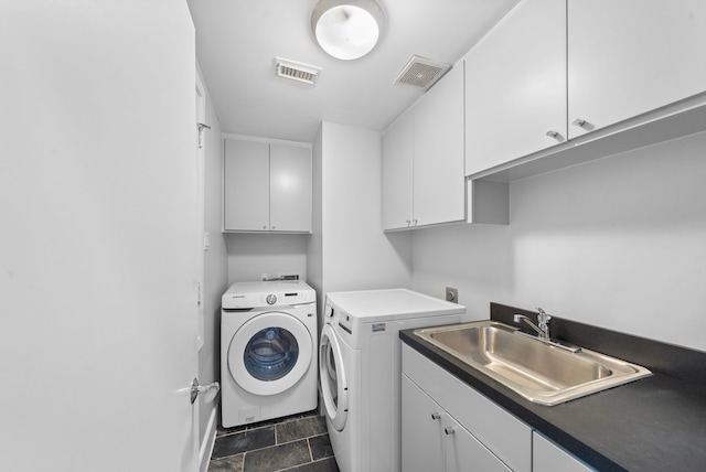 clothes washing area with washing machine and dryer, sink, and cabinets