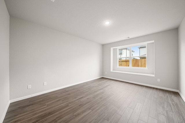 empty room featuring visible vents, baseboards, and wood finished floors