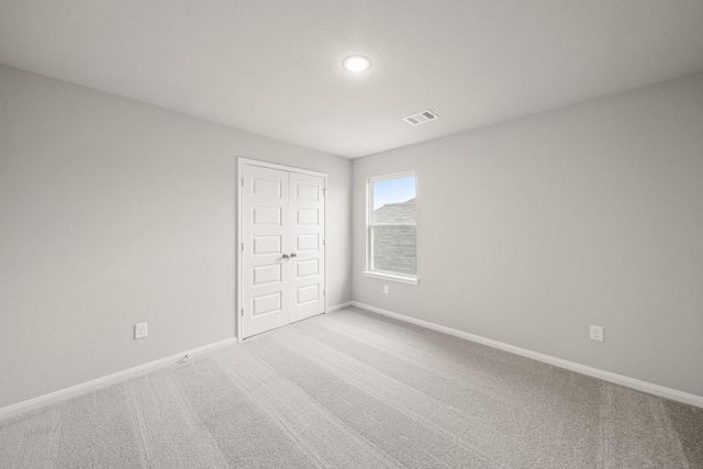 empty room with light colored carpet, visible vents, and baseboards