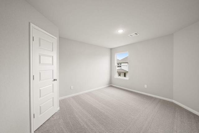 empty room with carpet, visible vents, and baseboards