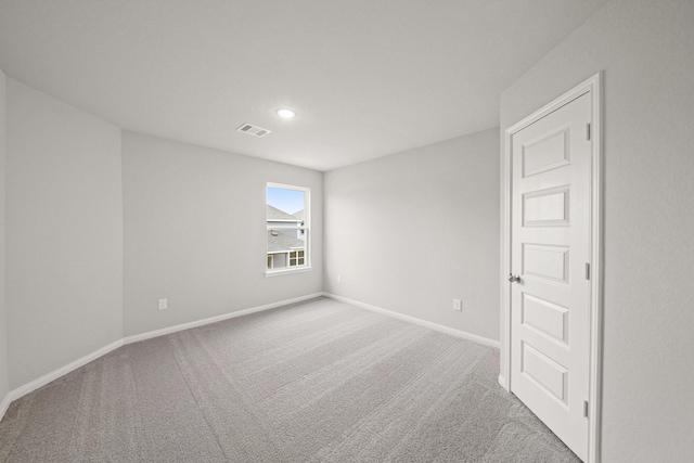 empty room featuring light colored carpet, visible vents, baseboards, and recessed lighting