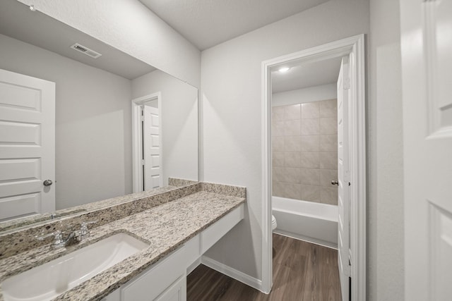 full bathroom with baseboards, visible vents, toilet, wood finished floors, and vanity