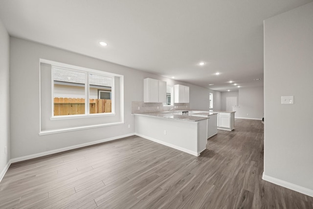 kitchen featuring a peninsula, white cabinets, wood finished floors, and recessed lighting