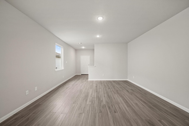 unfurnished room with recessed lighting, dark wood-style flooring, and baseboards