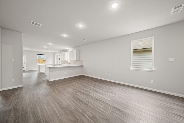 unfurnished living room with recessed lighting, wood finished floors, visible vents, and baseboards