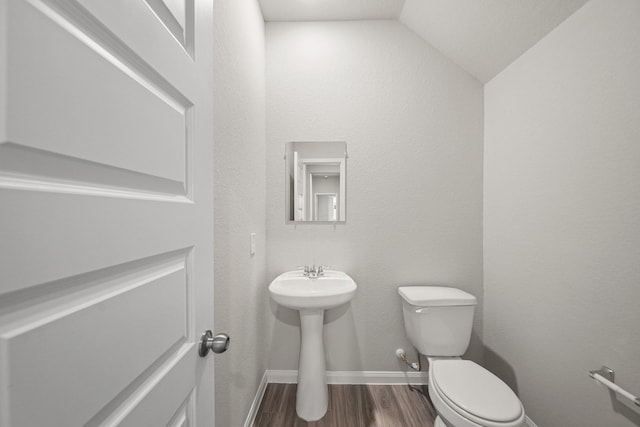 bathroom featuring vaulted ceiling, wood finished floors, toilet, and baseboards