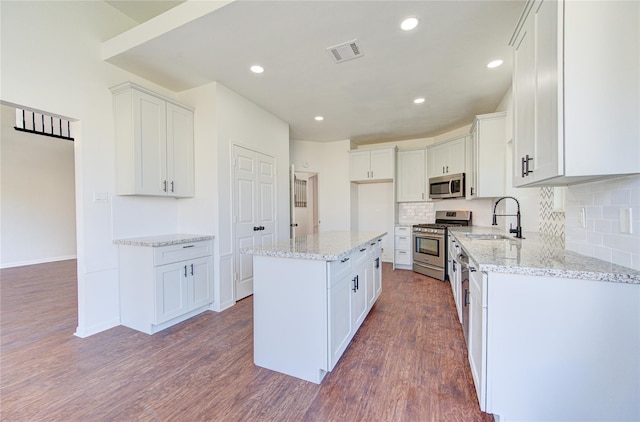 kitchen featuring stainless steel appliances, dark wood-type flooring, sink, white cabinets, and a center island