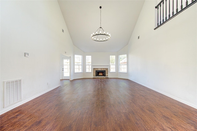 unfurnished living room with a fireplace, high vaulted ceiling, a chandelier, and dark hardwood / wood-style floors