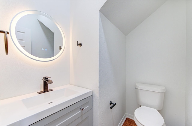 bathroom featuring vanity, toilet, and lofted ceiling