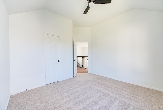 interior space with a closet, light colored carpet, vaulted ceiling, and ceiling fan