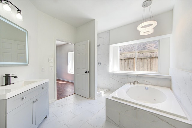 bathroom with tiled bath, a wealth of natural light, and vanity