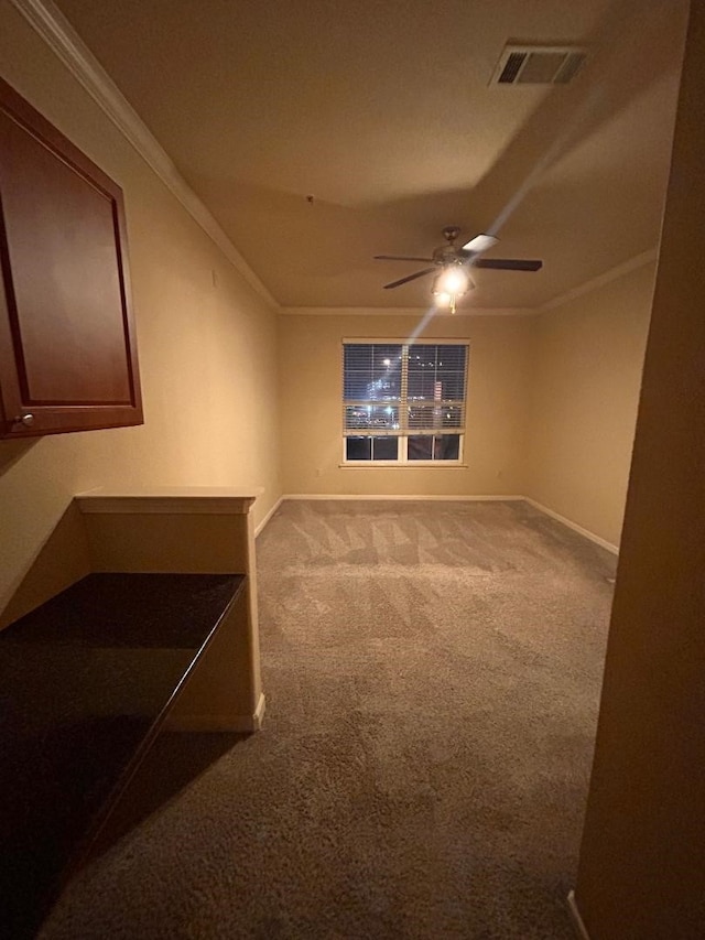 empty room featuring carpet floors, ceiling fan, and crown molding