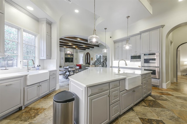 kitchen featuring a center island with sink, stainless steel appliances, gray cabinetry, and sink