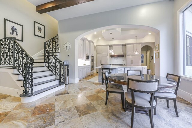 dining area featuring beam ceiling and sink