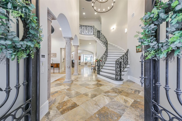 foyer entrance with ornate columns, a towering ceiling, and a notable chandelier