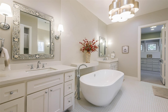 bathroom with vanity, a tub to relax in, and an inviting chandelier