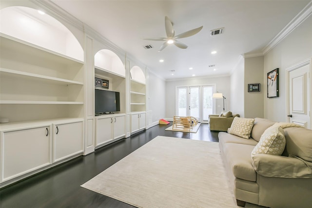 living room with built in shelves, ceiling fan, french doors, dark wood-type flooring, and crown molding