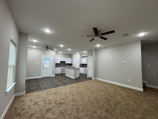 unfurnished living room featuring ceiling fan and dark carpet