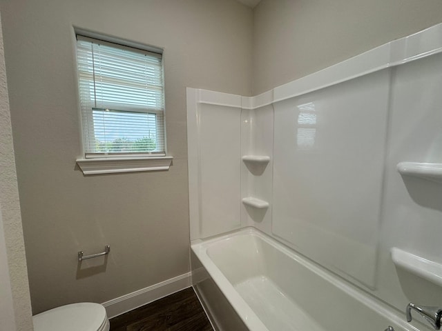 bathroom featuring hardwood / wood-style flooring, toilet, and bathtub / shower combination