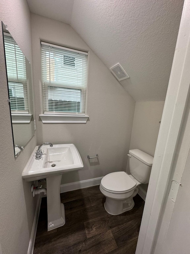 bathroom with hardwood / wood-style floors, a textured ceiling, toilet, and lofted ceiling