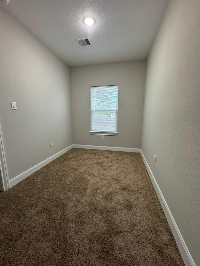 carpeted empty room featuring a textured ceiling