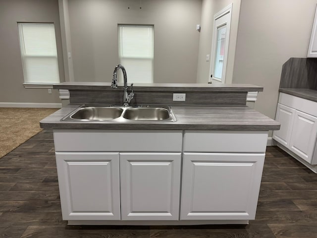 kitchen with dark colored carpet, sink, white cabinetry, and a kitchen island with sink