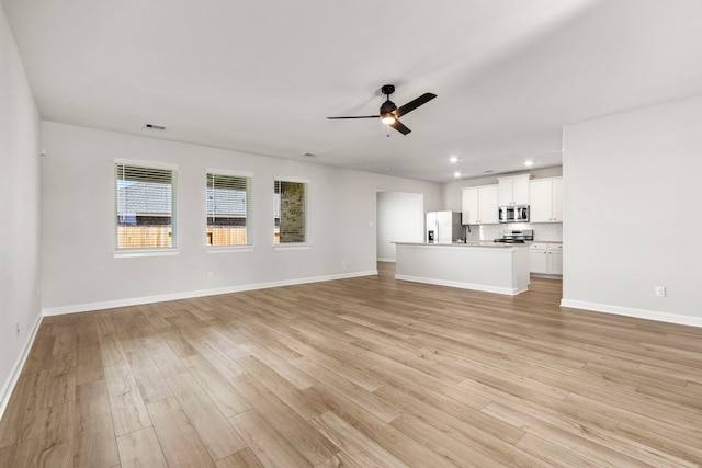 unfurnished living room featuring ceiling fan and light hardwood / wood-style floors