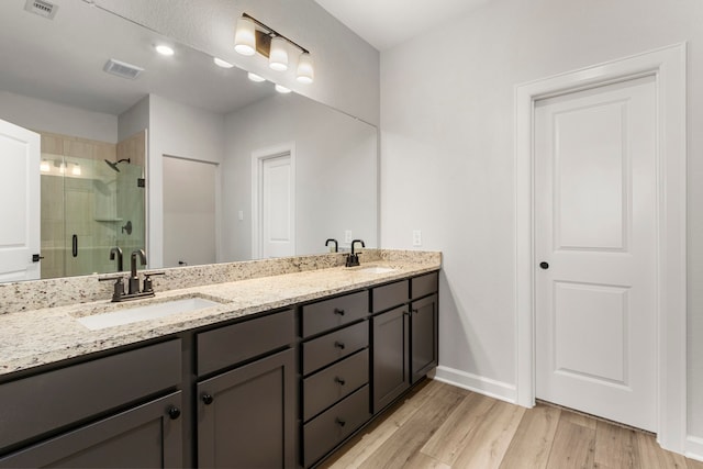 bathroom featuring wood-type flooring, vanity, and a shower with shower door