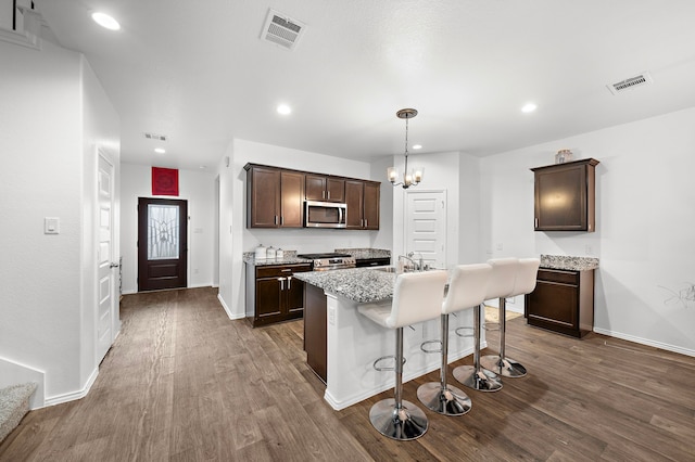 kitchen with a center island with sink, sink, appliances with stainless steel finishes, dark brown cabinets, and dark hardwood / wood-style flooring