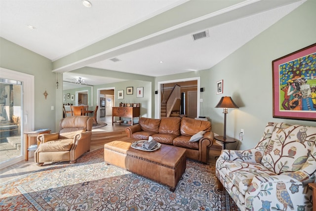 living area with stairs, wood finished floors, visible vents, and vaulted ceiling with beams