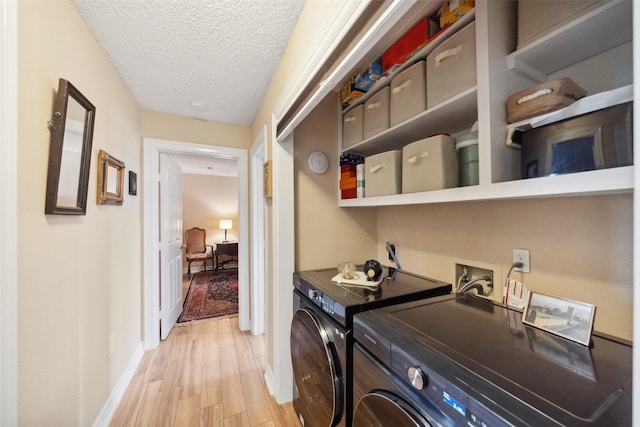 laundry room with laundry area, light wood finished floors, baseboards, washing machine and clothes dryer, and a textured ceiling