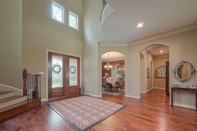 foyer featuring a chandelier, hardwood / wood-style floors, french doors, and crown molding