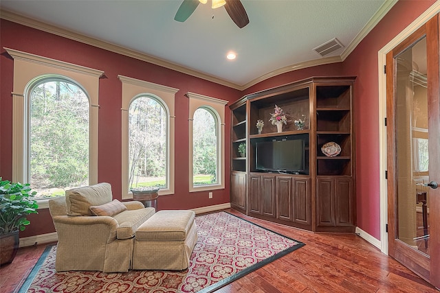 sitting room featuring wood-type flooring, ceiling fan, and ornamental molding