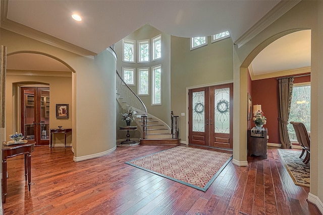 entrance foyer featuring french doors, a towering ceiling, hardwood / wood-style flooring, and crown molding