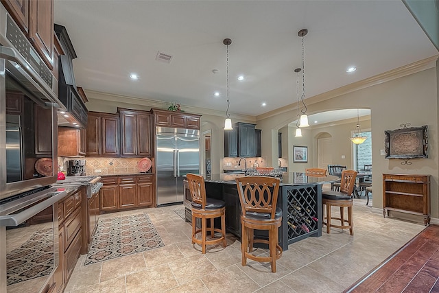 kitchen featuring tasteful backsplash, a center island with sink, a breakfast bar area, and stainless steel built in refrigerator