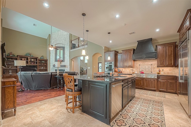 kitchen with premium range hood, a center island with sink, sink, ceiling fan, and ornamental molding