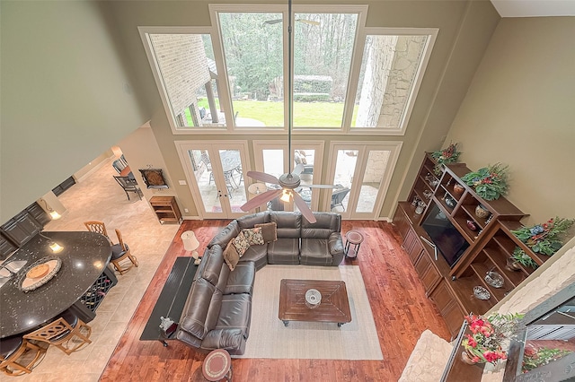 living room with hardwood / wood-style floors, ceiling fan, a high ceiling, and french doors