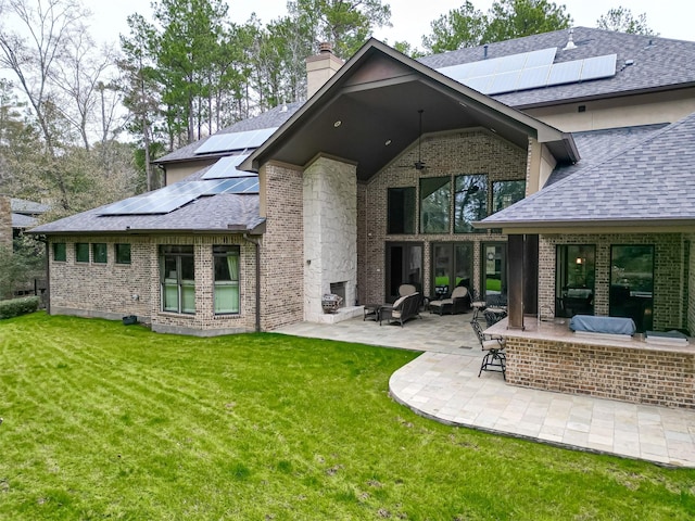 rear view of house featuring a yard, a patio, and solar panels