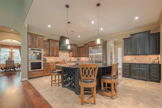 kitchen with stainless steel appliances, light hardwood / wood-style flooring, a large island with sink, a breakfast bar area, and custom exhaust hood