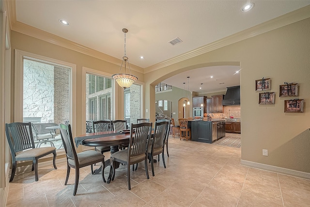 dining area with sink, light tile patterned flooring, ornamental molding, and an inviting chandelier