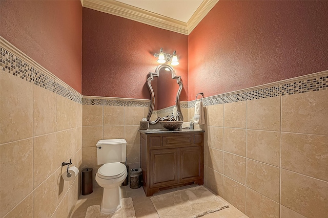 bathroom with tile patterned floors, ornamental molding, vanity, tile walls, and toilet