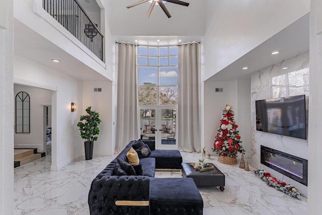 living room featuring a fireplace, french doors, and a towering ceiling