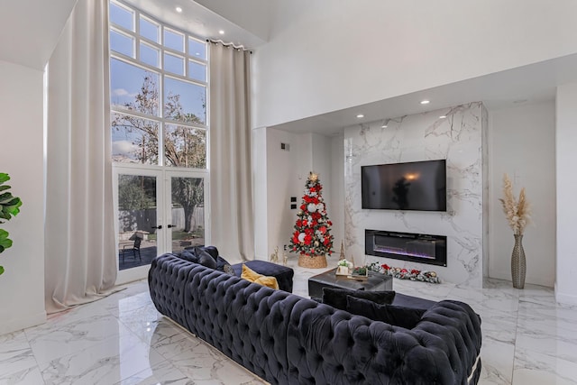 living room featuring a fireplace, french doors, and a towering ceiling