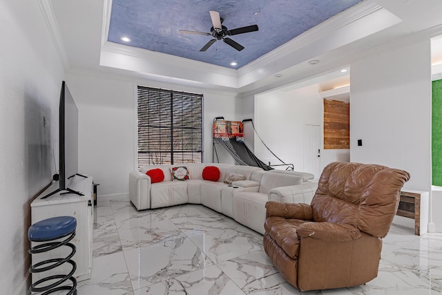 living room featuring a raised ceiling, ceiling fan, and ornamental molding