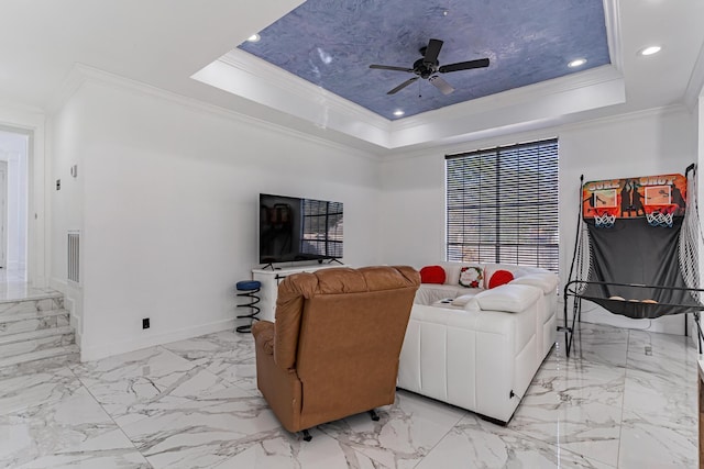 living room featuring ceiling fan, a raised ceiling, and ornamental molding